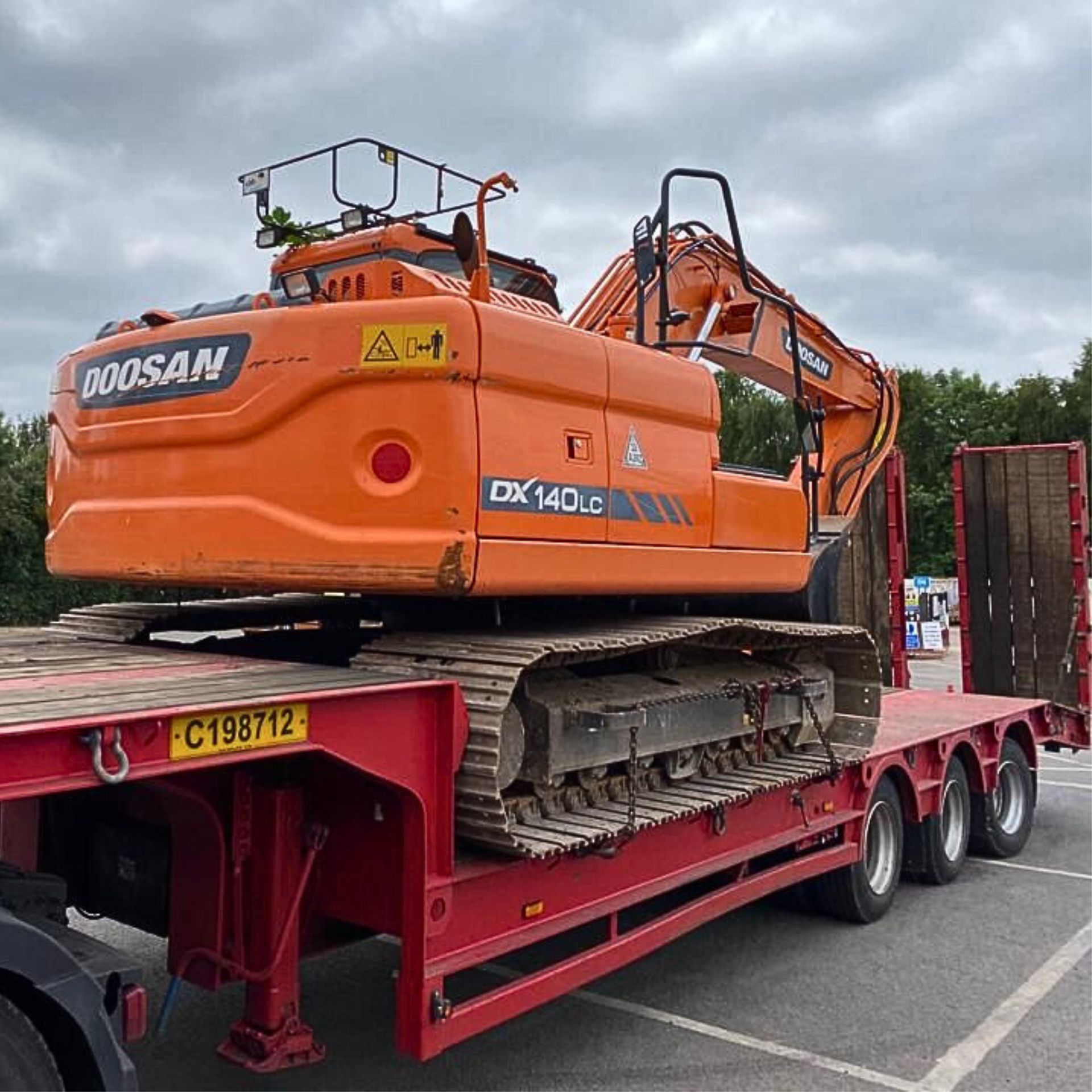 A small digger being transported by lorry