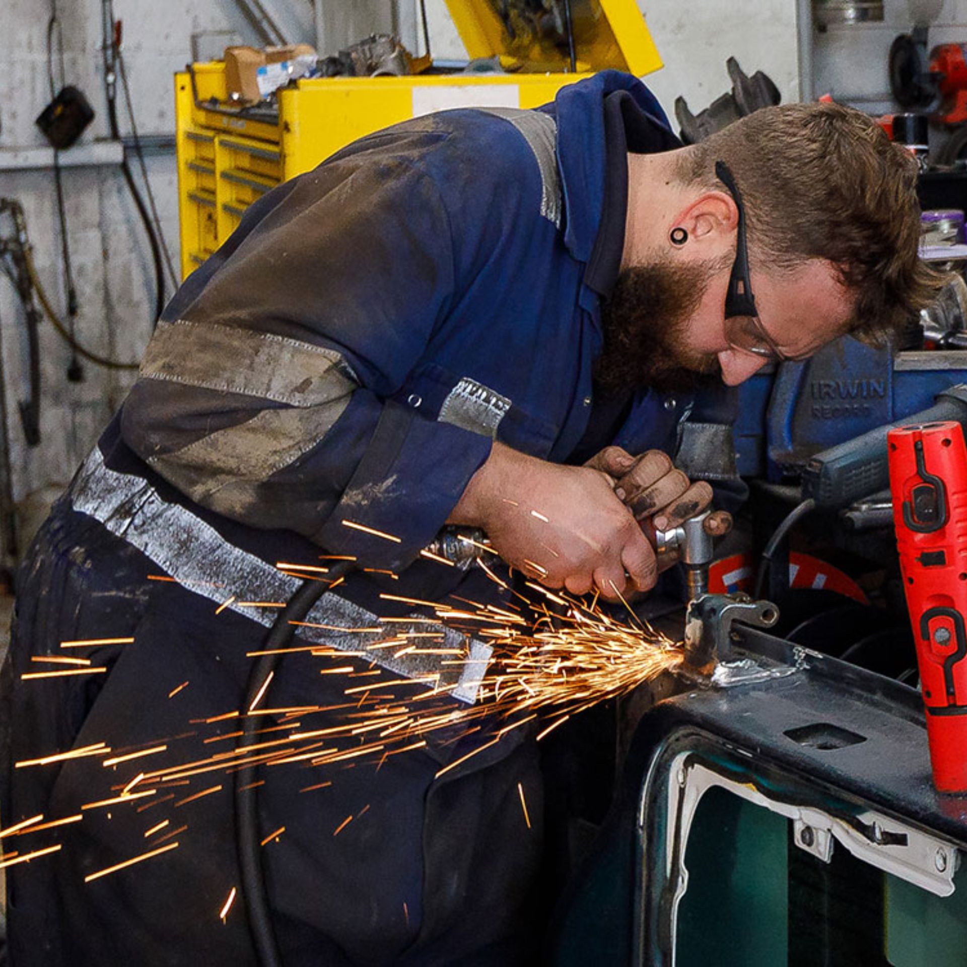 A mechanic using an angle grinder in a workshop