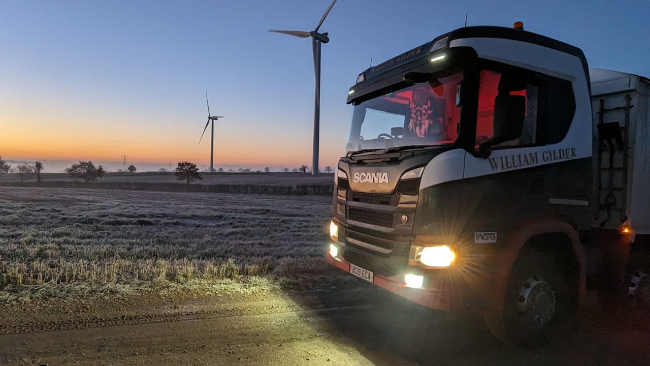 A lorry passing a wind turbine during winter