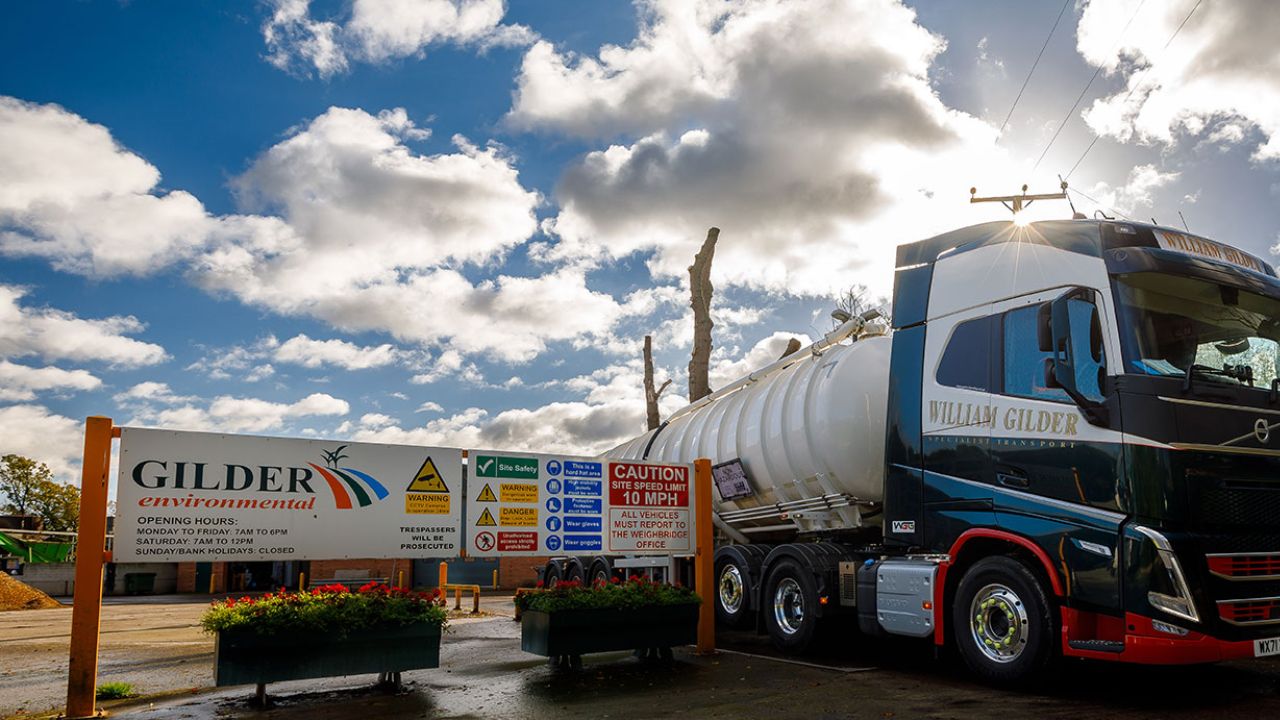 A lorry next to the entrance to a site with a sign